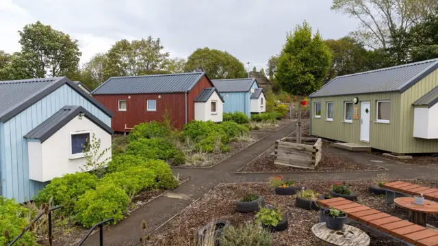 Small houses painted in different colours around a garden